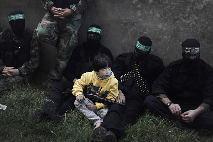 Những hình ảnh ấn tượng trong tuần ảnh 9 Dec. 7, 2012. A boy sits with masked militants from the Ezzedine al-Qassam brigades, the armed wing of the Hamas movement, as they rest after patrolling the streets of Gaza city. Read more: http://lightbox.time.com/2012/12/14/pictures-of-the-week-december-7-december-14/#ixzz2F8JEyI77