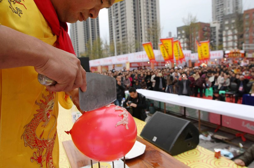 A chef demonstrates his skills with a knife by slicing meat balanced on top of a balloon. Chen Zibao showed off his delicate touch by cutting raw pork slices using a large cleaver on top of the balloon without popping it, in Wanzhou, Sichuan Province, China.