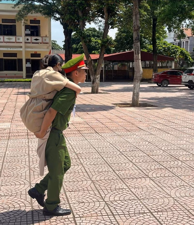 Trung uý Vũ Mạnh Cường - Cán bộ Đội điều tra tổng hợp, Công an huyện Thanh Thuỷ cõng thí sinh bị khuyết tật vào điểm thi trường THPT Trung Nghĩa, Phú Thọ. (Ảnh: Công an tỉnh Phú Thọ).