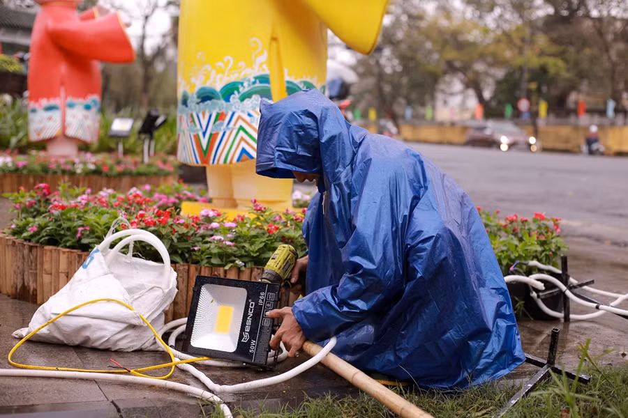 Công nhân đang tu sửa lại đèn chiếu cho 2 tượng mèo.