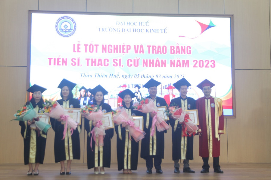 Các tân thạc sĩ có thành tích học tập tốt nhận hoa chúc mừng từ nhà trường. (Ảnh: Đại Dương).