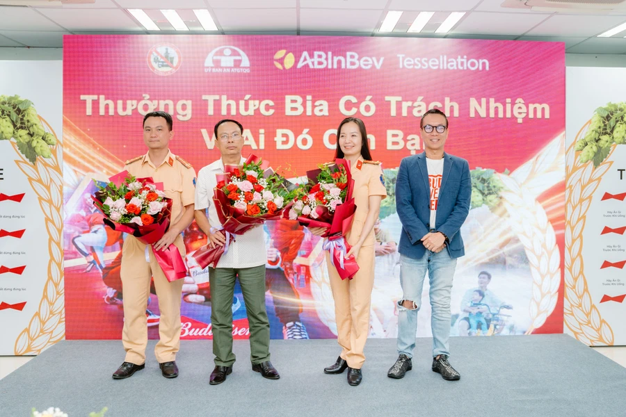 Đại diện công ty AB InBev tặng hoa cho ông Lê Xuân Cử (áo trắng), Chánh Văn phòng Ban ATGT tỉnh Hoà Bình và cán bộ Phòng CSGT tỉnh Hòa Bình.