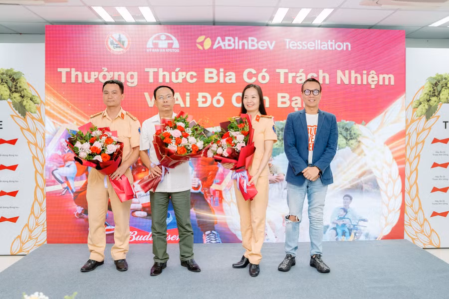 Đại diện công ty AB InBev tặng hoa cho ông Lê Xuân Cử (áo trắng), Chánh Văn phòng Ban ATGT tỉnh Hoà Bình và cán bộ Phòng CSGT tỉnh Hòa Bình.