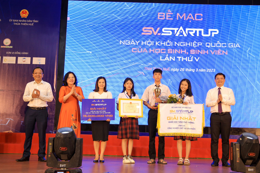 Thứ trưởng Ngô Thị Minh (thứ 2, từ trái qua) và Phó Chủ tịch Thường trực UBND tỉnh Thừa Thiên - Huế - ông Nguyễn Thanh Bình (ngoài cùng, bên phải) trao giải nhất khối học sinh phổ thông trong lĩnh vực: công nghiệp chế tạo sản phẩm của nhóm học sinh Trường THPT Phú Bài (tỉnh Thừa Thiên - Huế).