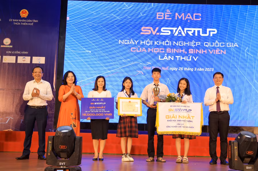 Thứ trưởng Ngô Thị Minh (thứ 2, từ trái qua) và Phó Chủ tịch Thường trực UBND tỉnh Thừa Thiên - Huế - ông Nguyễn Thanh Bình (ngoài cùng, bên phải) trao giải nhất khối học sinh phổ thông trong lĩnh vực: công nghiệp chế tạo sản phẩm của nhóm học sinh Trường THPT Phú Bài (tỉnh Thừa Thiên - Huế).