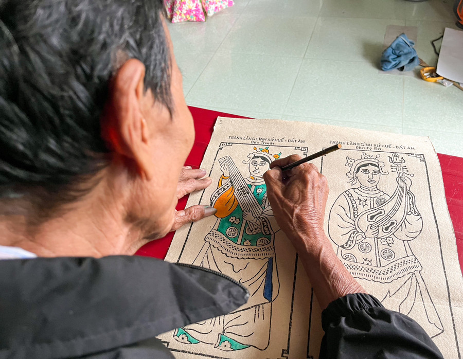Nghệ nhân Kỳ Hữu Phước đang tập trung, tỉ mỉ tô màu từng chi tiết cho các bức tranh.