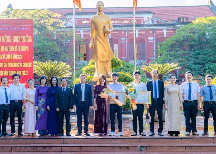 Đại diện lãnh đạo, Sở GD&amp;ĐT, Ban cha mẹ học sinh chụp ảnh lưu niệm cùng 2 học sinh.