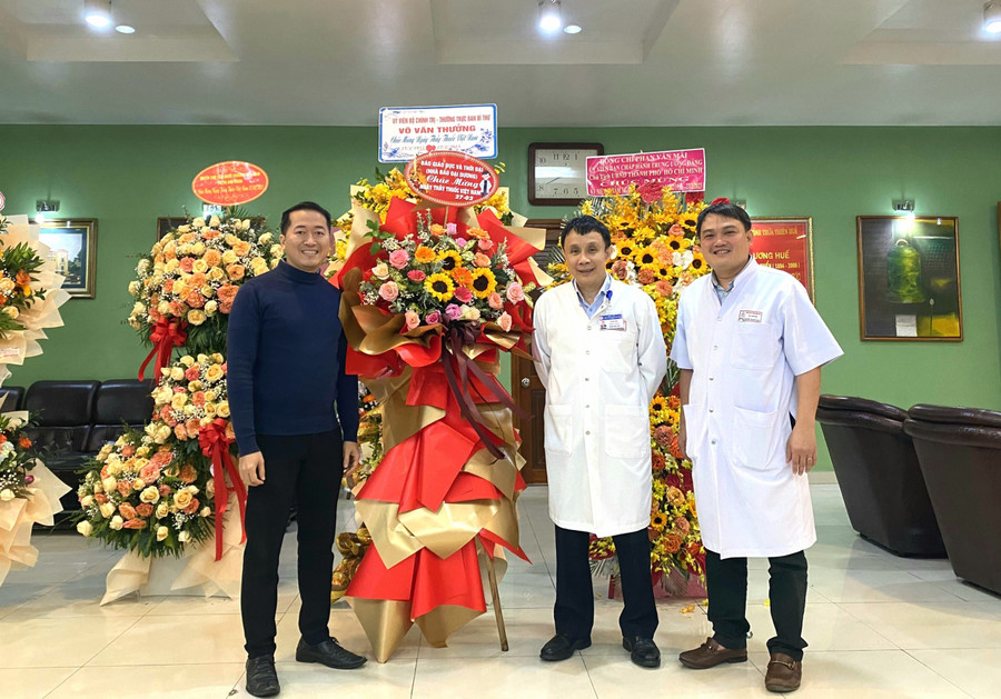 GS.TS. Phạm Như Hiệp - Giám đốc Bệnh viện Trung ương Huế (giữa) và TS. Nguyễn Thanh Xuân - Phó Giám đốc Bệnh viện Trung ương Huế (ngoài cùng bên phải) đón nhận lẵng hoa chúc mừng của Báo Giáo dục và Thời đại. (Ảnh: Hoàng Hải).