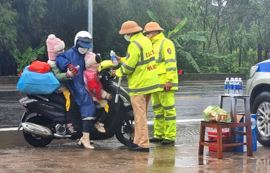 Mẹ và 2 con nhỏ bất ngờ khi được các chú CSGT phát quà đầu năm.