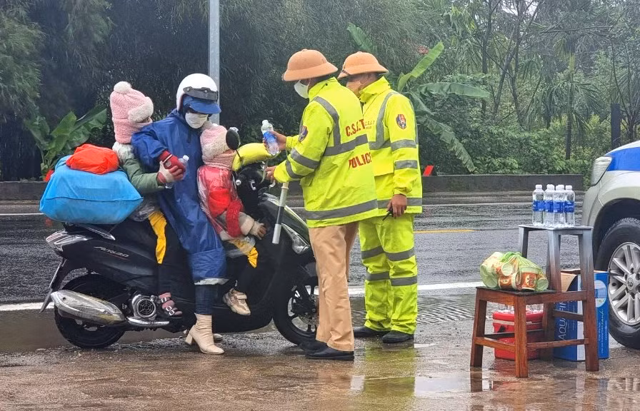 Mẹ và 2 con nhỏ bất ngờ khi được các chú CSGT phát quà đầu năm.