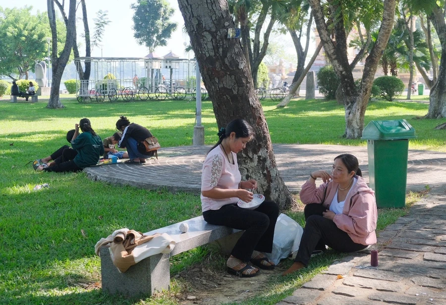 Chị Hồ Thị Nhàn (ngồi trên ghế đá) tranh thủ làm sản phẩm thủ công người dân tộc thiểu số trong lúc chờ con thi tốt nghiệp THPT (Ảnh: L. Nguyễn).