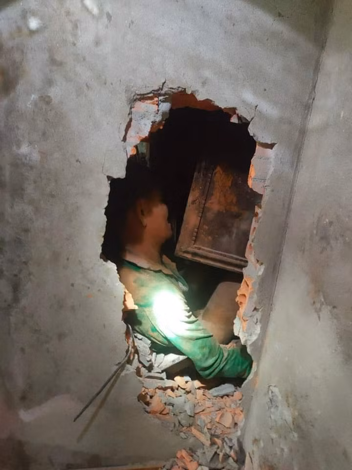 Công an khoan tường đưa người chồng bị mắc kẹt ra ngoài.