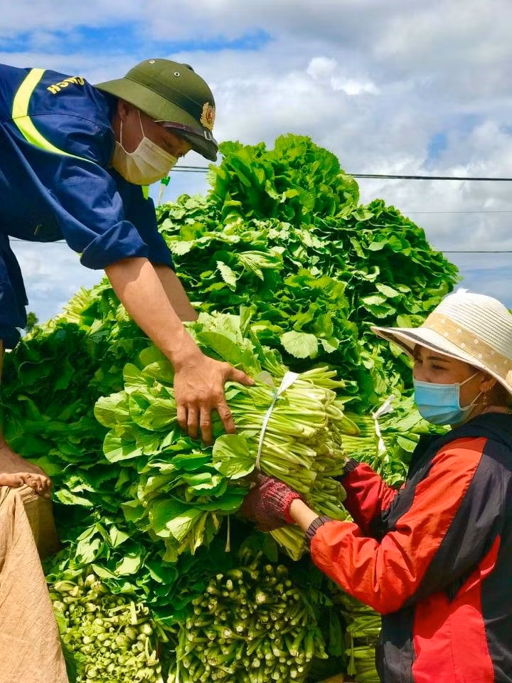 Cán bộ, chiến sỹ và người dân vận chuyển rau, củ lên xe.