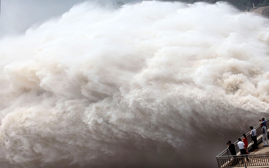 Người dân đứng trên bờ của đập nước Xiaolangdi nhìn xuống dòng sông Hoàng Hà khi nước lụt được xả lần thứ 2 kể từ cuối tháng 6 tại đây. People on the edge of the Xiaolangdi reservoir look on as the Yellow River floodwaters are released for the second time since the end of June in Xiaolangdi, in central China