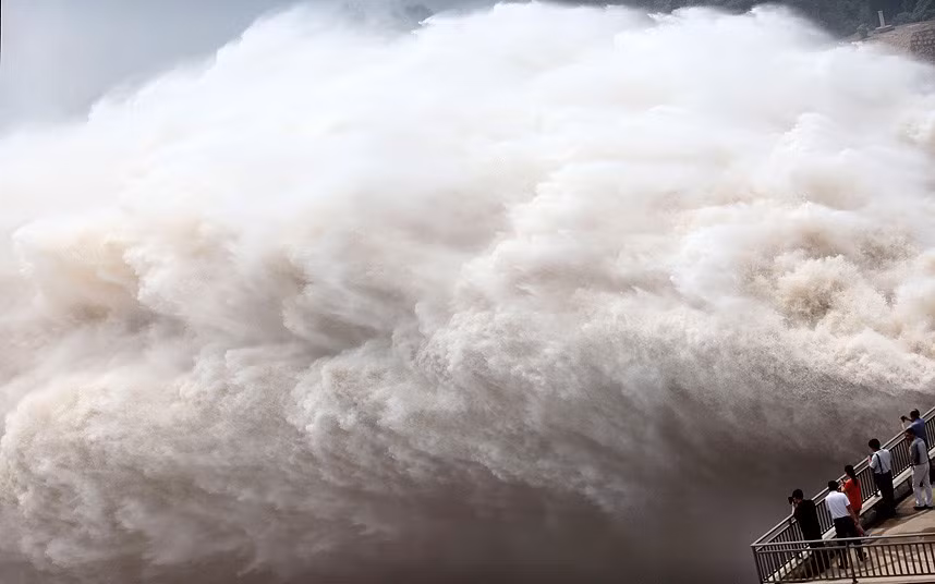 Người dân đứng trên bờ của đập nước Xiaolangdi nhìn xuống dòng sông Hoàng Hà khi nước lụt được xả lần thứ 2 kể từ cuối tháng 6 tại đây. People on the edge of the Xiaolangdi reservoir look on as the Yellow River floodwaters are released for the second time since the end of June in Xiaolangdi, in central China