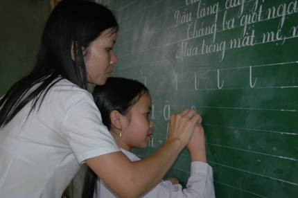 Cô cầm tay em, nắn từng nét chữ... Ảnh: Hoàng Đan c