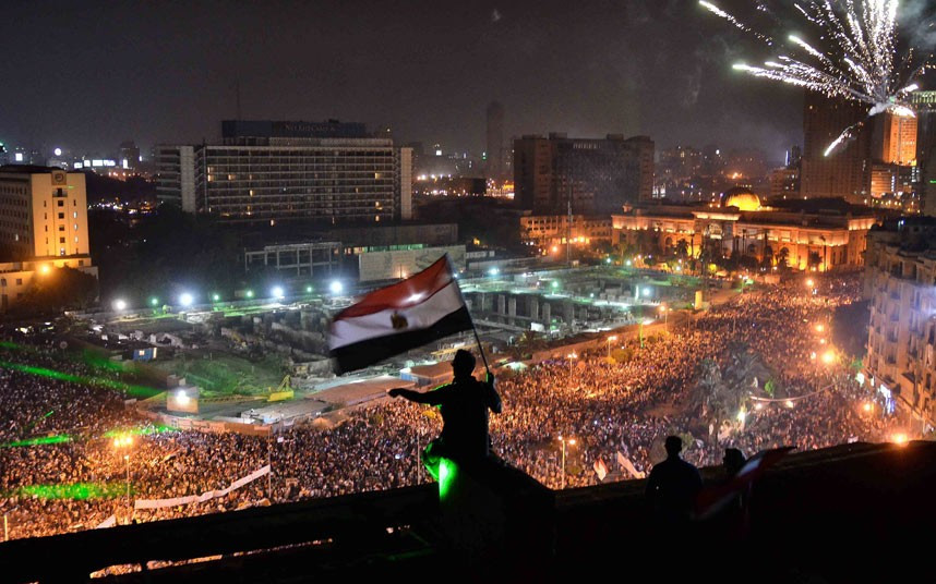 Egyptians wave the national flag from a building rooftop as hundreds of thousands flood Cairo