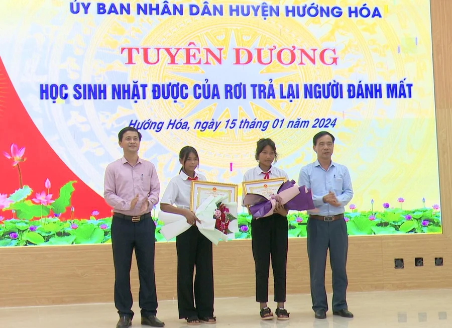 Ông Trần Bình Thuận, Chủ tịch UBND huyện (bên trái) và ông Phạm Trọng Hổ, Phó Chủ tịch UBND huyện đã biểu dương và tặng giấy khen cho hai học sinh Hồ Thị Hinh và Hồ Thị Nhỉ.