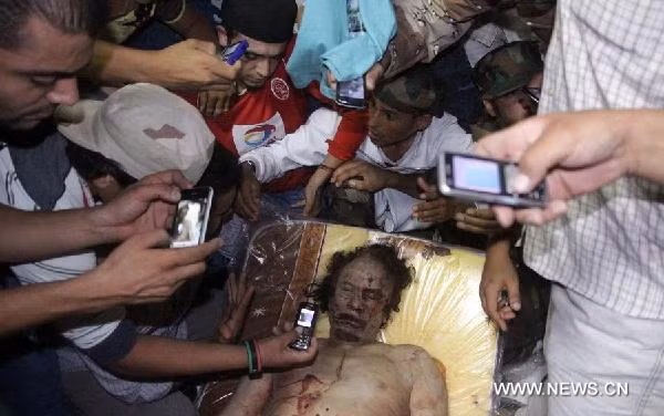 Local citizens gather around the body of Muammar Gaddafi in a house in the city of Misurata on Oct. 20, 2011. 