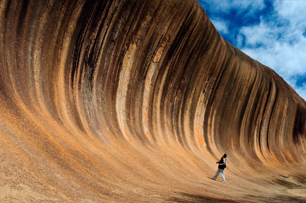 Những hình ảnh ấn tượng trong tuần ảnh 1 A tourist appears to be surfing as she stands under the lip of a massive rock which looks like a crashing wave. The multi-coloured granite formation, known as The Wave Rock, towers 47ft high and is 350ft long. The stunning natural structure is near the town of Hyden, Western Australia.