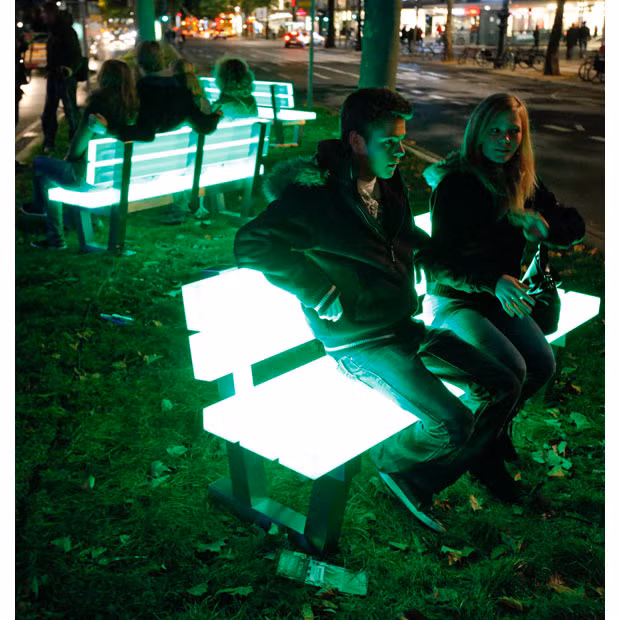 People sit on illuminated benches at the Kurfuerstendamm Boulevard during the Festival of Lights in Berlin