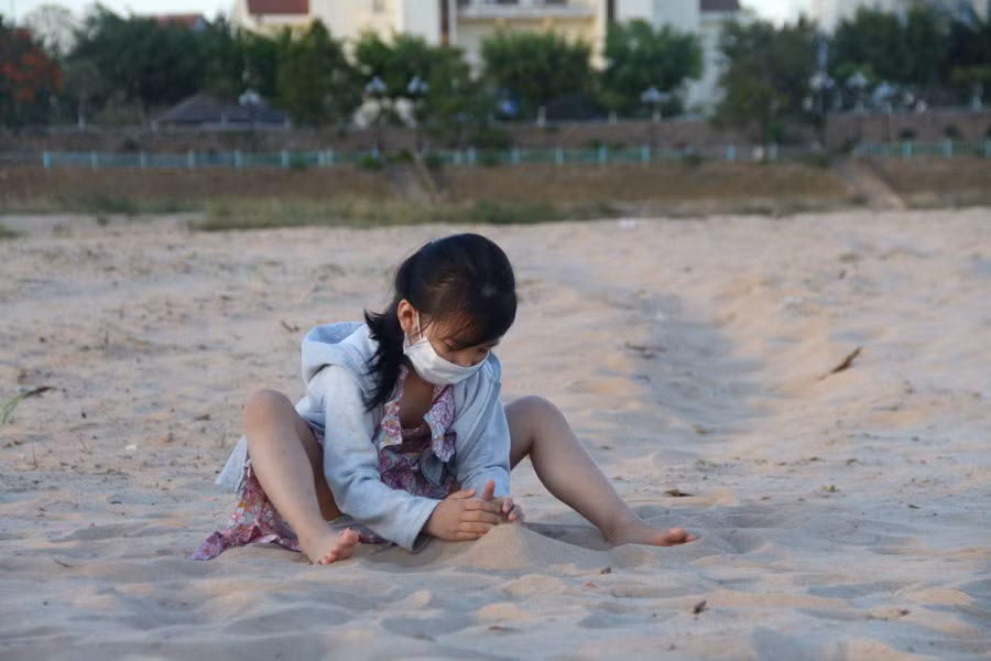 Cháu bé nghịch cát trên bãi bồi.