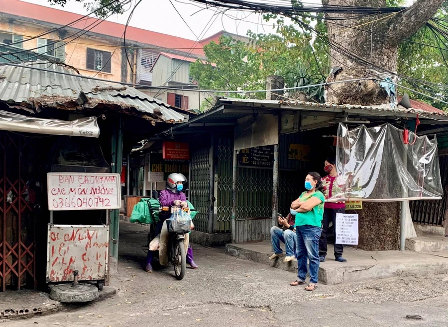 Trên trục đường chính, mặc dù đóng cửa hàng nhưng các tiểu thương vẫn đứng ngoài mời khách mua hàng.