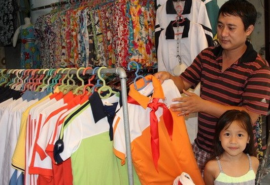 Anh Lưu Quang Huy đang lực chọn quần áo đồng phụ cho con tại cửa hàng Đức Hạnh trên phố Hàng Trống (Hà Nội)