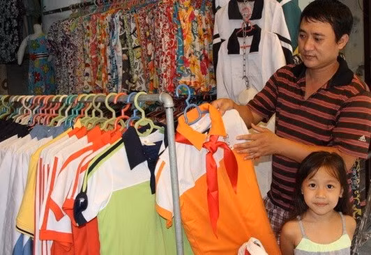 Anh Lưu Quang Huy đang lực chọn quần áo đồng phụ cho con tại cửa hàng Đức Hạnh trên phố Hàng Trống (Hà Nội)