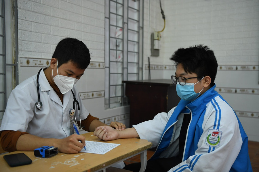 Trước khi vào phòng tiêm, học sinh được đo huyết áp, khám sàng lọc.