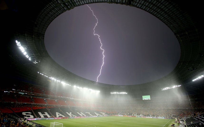 Những hình ảnh ấn tượng trong tuần ảnh 3 A bolt of lightning streaks across the sky above the Donbass Arena in Donetsk after the Euro 2012 match between France and Ukraine was suspended due to bad weather