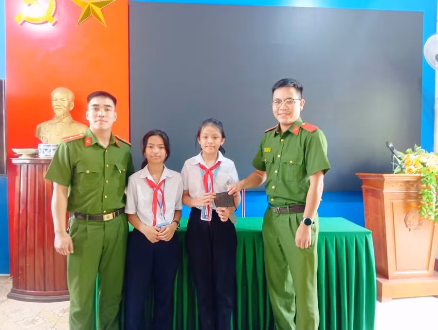 Hai em Trần Ngọc Bảo Ánh (lớp 6D) và em Nguyễn Thị Bảo Trang (học lớp 6A) giao lại chiếc ví cho Công an thị trấn Hồ Xá.