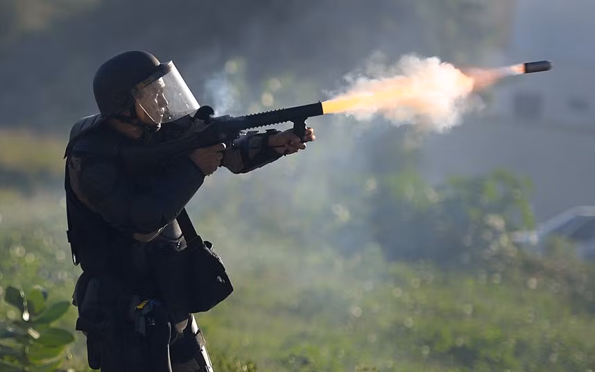 An anti riot police officer fires a tear grenade towards violent anti-government demonstrators at the security perimeter two kilometers (1.2 miles) from the Castelao stadium in Fortaleza where Spain and Italy play their FIFA Confederations Cup Brazil 2013 semi-final football match