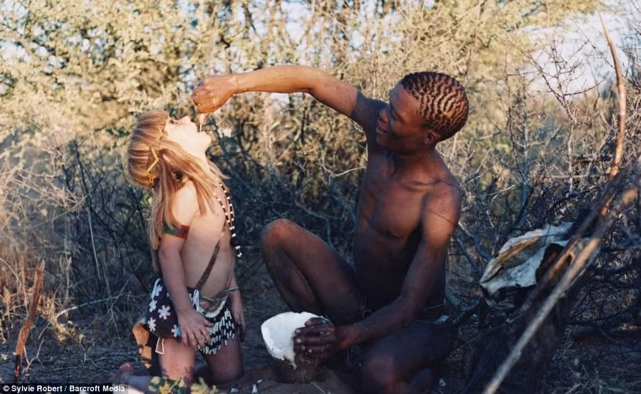 Thirsty work: Tkui of the San Bushmen of northern Namibia, feeds Tippi water from a root plant in Okavango Swamps Read more: http://www.dailymail.co.uk/news/article-2337418/The-REAL-Mowgli-Incredible-images-little-girl-spent-years-life-growing-African-bush.html#ixzz2ValHh6a5 Follow us: @MailOnline on Twitter | DailyMail on Facebook