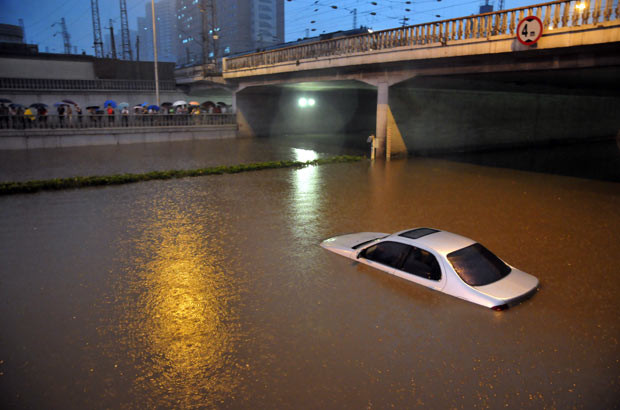Những hình ảnh ấn tượng trong tuần ảnh 6 A vehicle is trapped on a flooded street during a rainstorm in Beijing