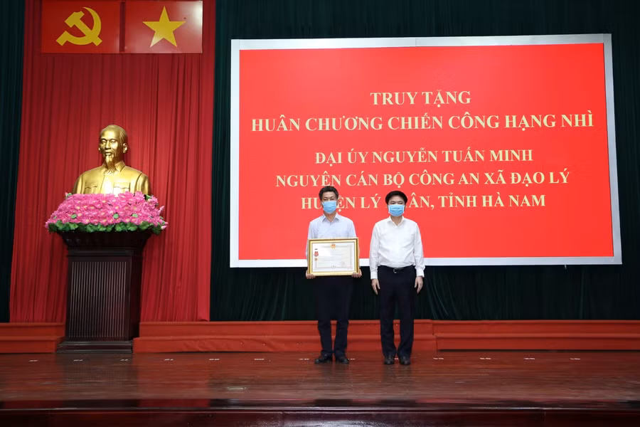 Thừa uỷ quyền của Chủ tịch nước Nguyễn Xuân Phúc, ông Trương Quốc Huy, Chủ tịch UBND tỉnh Hà Nam đã trao tặng Huân chương Chiến công hạng Nhì cho thân nhân gia đình Đại uý Nguyễn Tuấn Minh. Ảnh: Công an Hà Nam.