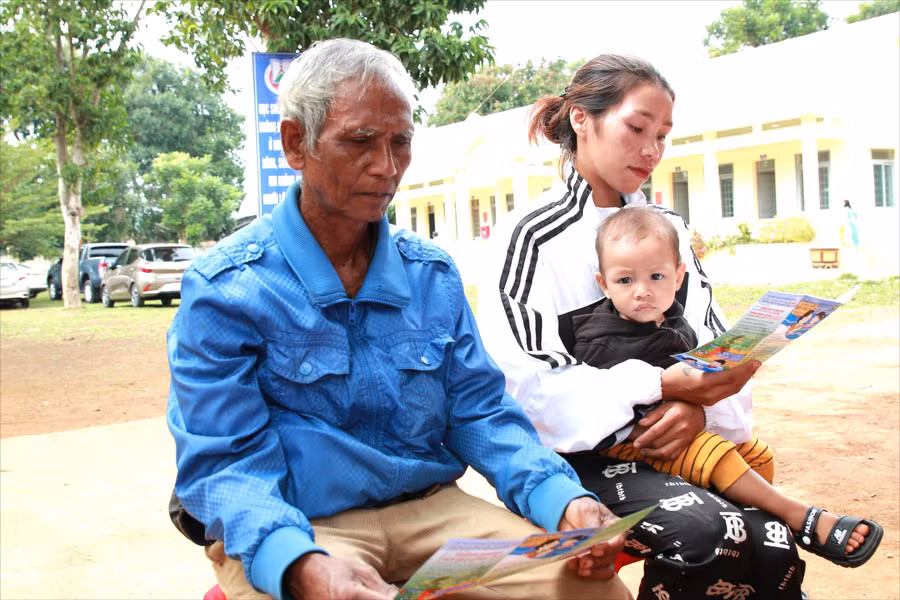 Người dân xã Cuôr Đăng, huyện Cư M'gar đọc tờ rơi phòng, chống đuối nước. (Ảnh: TT)