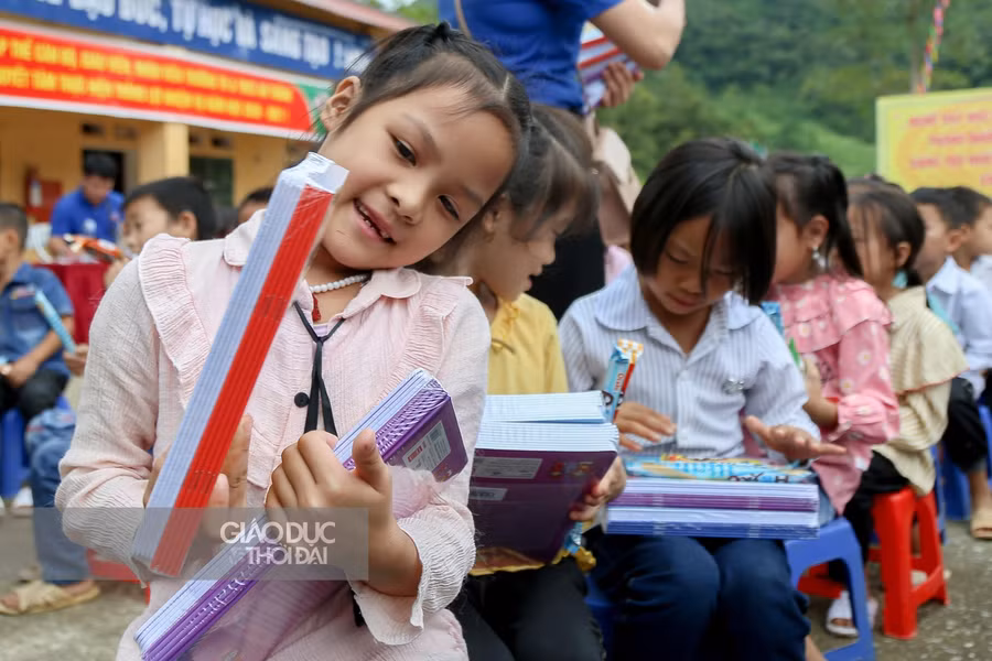 Những em học sinh vui vẻ khi cầm trên tay những cuốn vở viết mới.