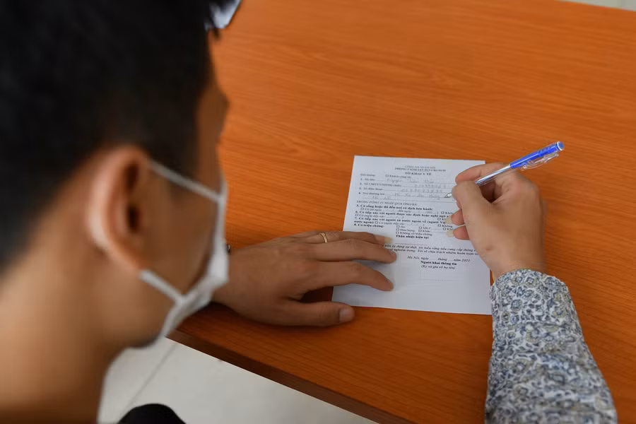 Người dân đến đều được hướng dẫn tận tình từ khai tờ khai y tế, nhắc nhở ngồi giãn cách theo đúng quy định.