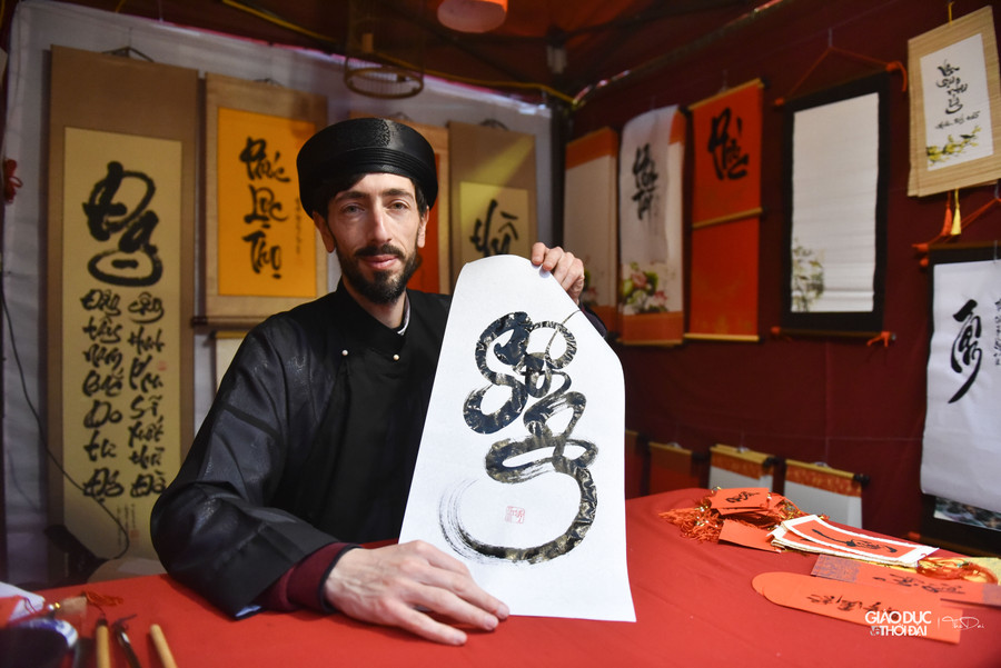Anh Jean - Sébastien Grill (42 tuổi, quốc tịch Pháp) trong trang phục áo the, khăn xếp, đang uyển chuyển đưa nét theo chiếc bút lông. Anh là &quot;ông Tây&quot; viết thư pháp duy nhất trong Hội chữ năm nay, do đó nhận được sự chú ý của nhiều người.