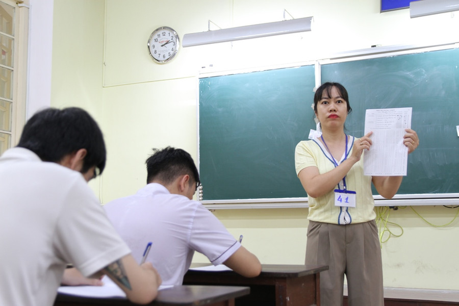 Một nữ cán bộ coi thi hướng dẫn cách thức điền thông tin trên tờ giấy thi. Một nữ cán bộ coi thi hướng dẫn cách thức điền thông tin trên tờ giấy thi.