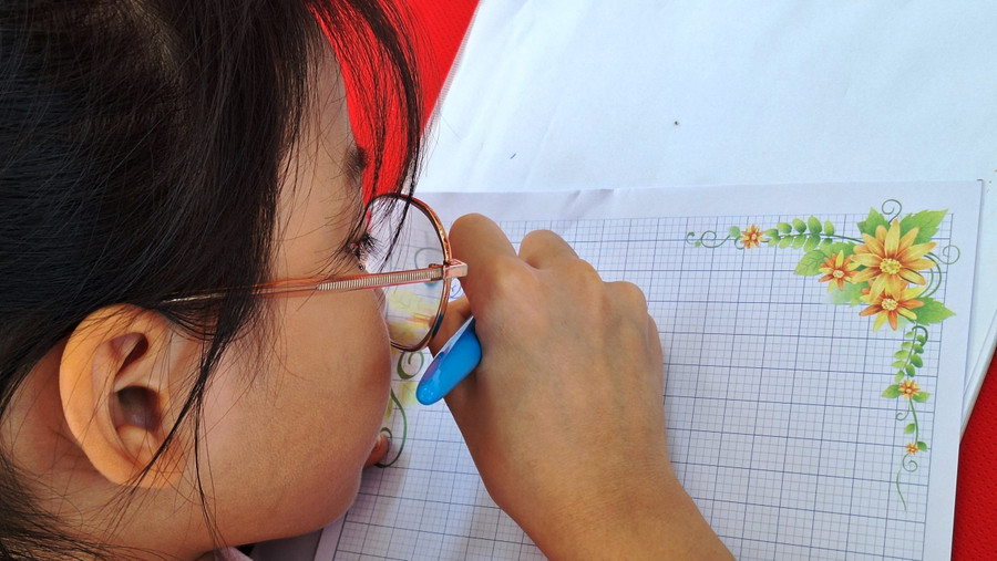 Một nữ sinh chăm chú nắn nót nét chữ.