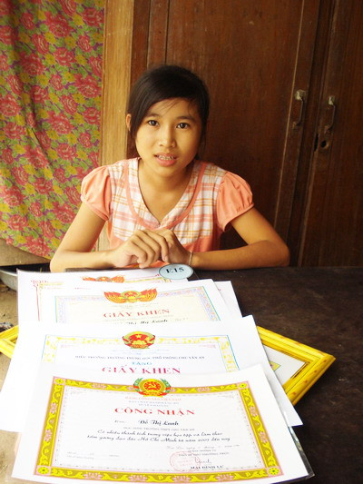  Đỗ Thị Mỹ Lành (học lớp 9) em của Lanh bên những giấy khen của các chị em trong thời gian qua.