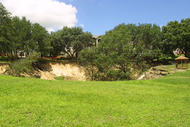 Kinh hoàng những hố địa ngục trên thế giới ảnh 26 A sinkhole measuring 150 feet wide and about 60 feet deep is shown on June 12, 2002, a day after it opened near the Woodhill Apartments in Orlando, Florida