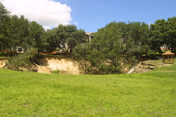 A sinkhole measuring 150 feet wide and about 60 feet deep is shown on June 12, 2002, a day after it opened near the Woodhill Apartments in Orlando, Florida