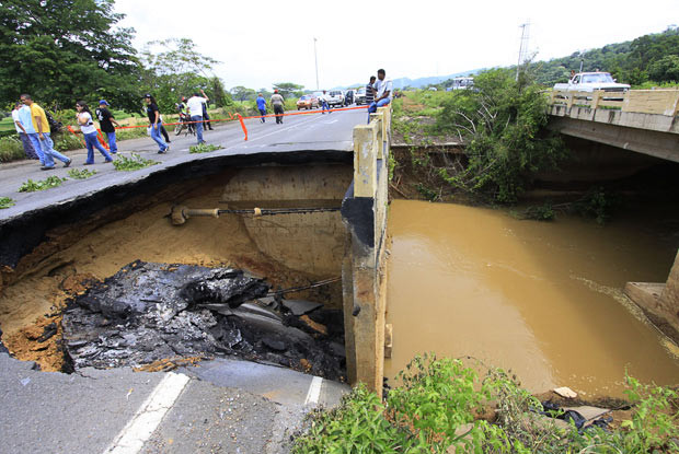 Kinh hoàng những hố địa ngục trên thế giới ảnh 4 July 2010: People walk past part of a highway that collapsed in Estado Anzoategui, Venuzuela. One person was killed and two others injured during the highway subsidence