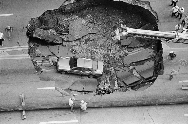 Kinh hoàng những hố địa ngục trên thế giới ảnh 19 Workers repair electrical lines from the basket of a crane and from the perimeter of a massive sinkhole that appeared in West Broad Street in Columbus, Ohio. A Mercedes-Benz driven by local lawyer Michael M. Schmidt lies at the bottom of the crater. The sinkhole was caused by a sewer line that collapsed