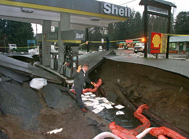 Kinh hoàng những hố địa ngục trên thế giới ảnh 21 A petrol station employee soaks up spilled fuel after the pumps sank six feet into a sinkhole in the Seattle suburb of Lake Forest Park, in January 1997. Heavy snow and rain storms in the Pacific Northwest caused major flooding and property damage