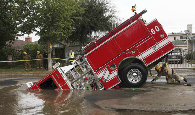 Kinh hoàng những hố địa ngục trên thế giới ảnh 25 A Los Angeles fireman looks under a fire truck stuck in a sinkhole in the Valley Village neighbourhood of Los Angeles, in this September 2009 photo. Four firefighters escaped injury after their fire engine sank into a large hole caused by a burst water main in the San Fernando Valley
