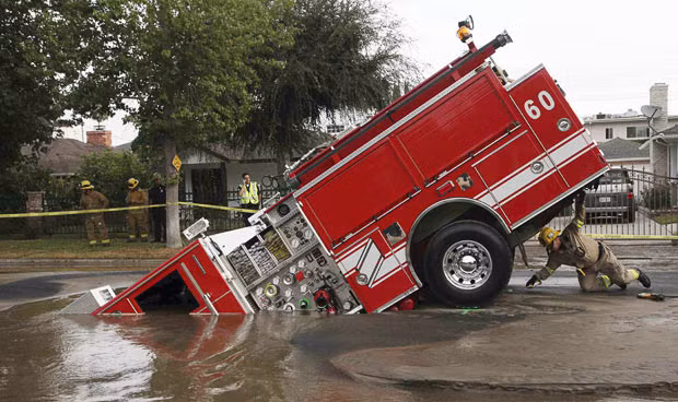 A Los Angeles fireman looks under a fire truck stuck in a sinkhole in the Valley Village neighbourhood of Los Angeles, in this September 2009 photo. Four firefighters escaped injury after their fire engine sank into a large hole caused by a burst water main in the San Fernando Valley